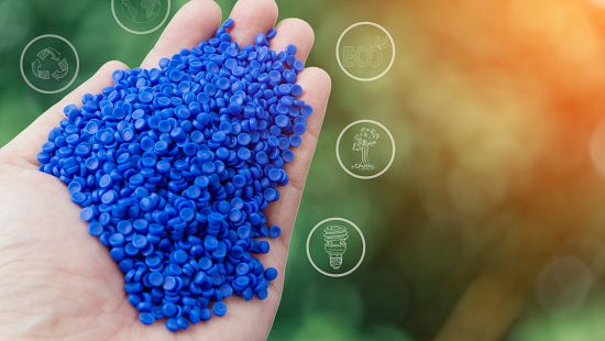 hands holding blue plastic pellets